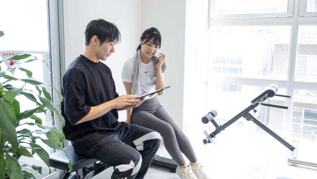 男性トレーナーが女性客とカウンセリングをしている様