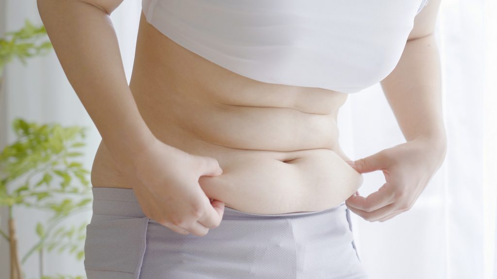 下腹部をつまむ女性