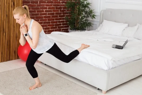 自宅の寝室で下半身トレーニングを行う女性の様子