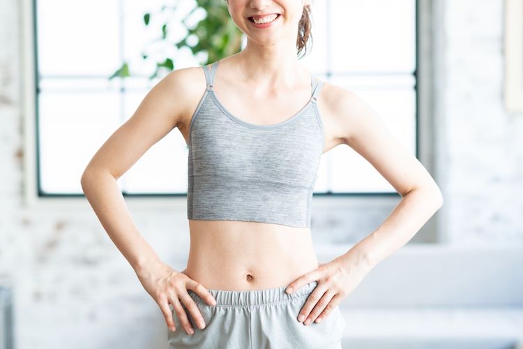 スポーツウェアを着た女性がウエスト周りを見せて立っている様子。体重より見た目の変化をイメージさせる写真。