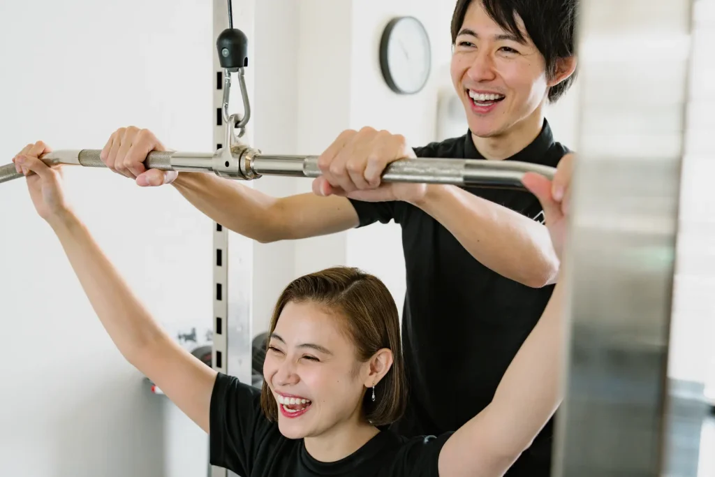 女性トレーナーと笑顔でトレーニングを行う女性。