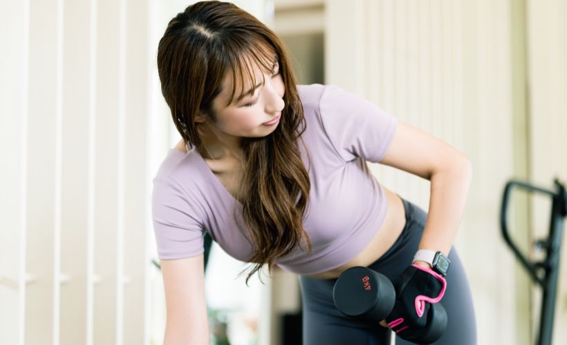 自宅でダンベルを使いトレーニングを行う女性
