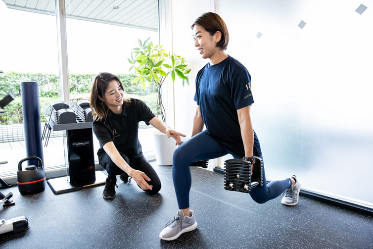 女性がトレーナーの指導を受けながらパーソナルトレーニングを行う様子